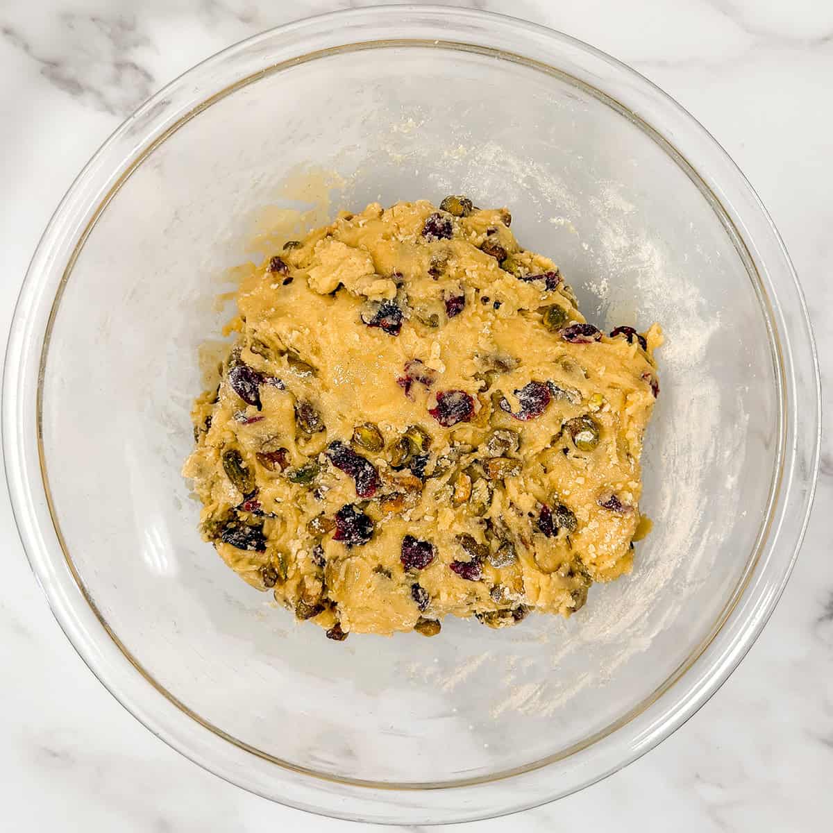 Mixing biscotti batter in a glass bowl.