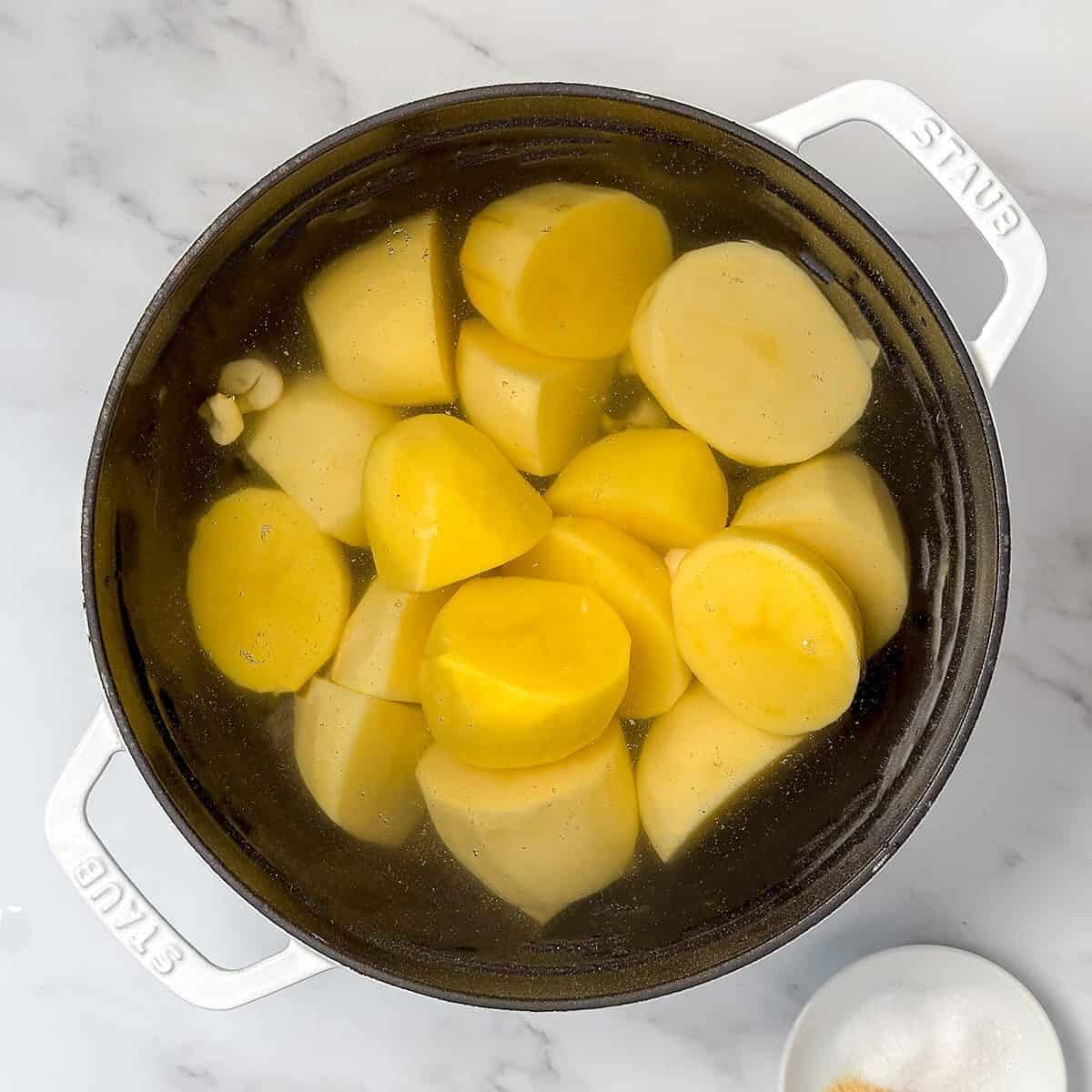 Cut potatoes and garlic in a Dutch oven covered with water.
