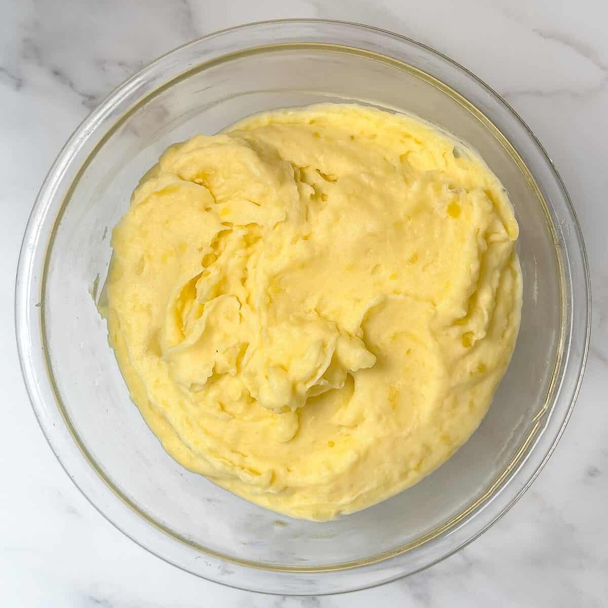 Garlic mashed potatoes, whipped and seasoned in a large glass bowl.