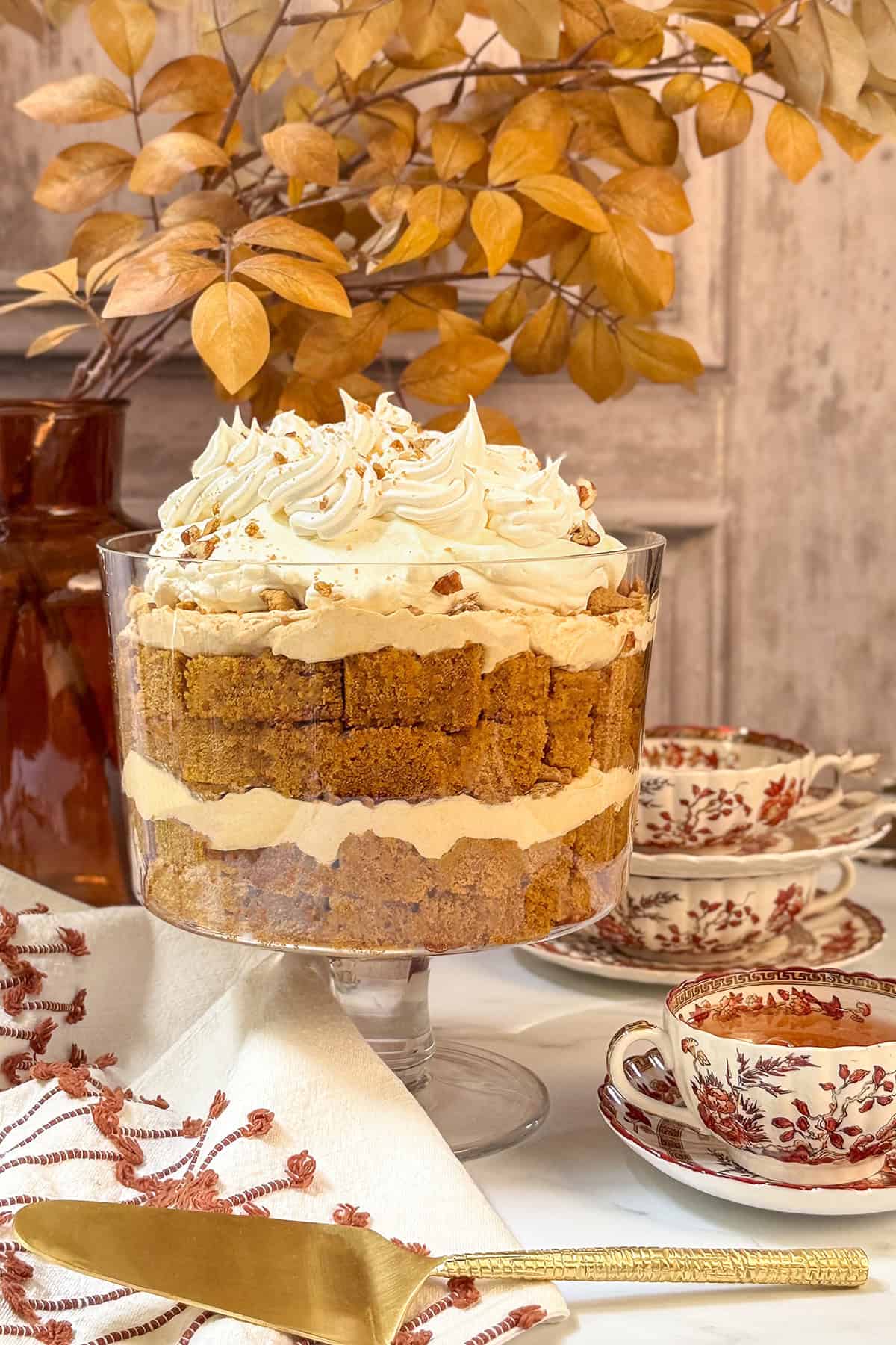 A pumpkin trifle in a glass serving dish with tea in a Spode teacup, ready for serving.