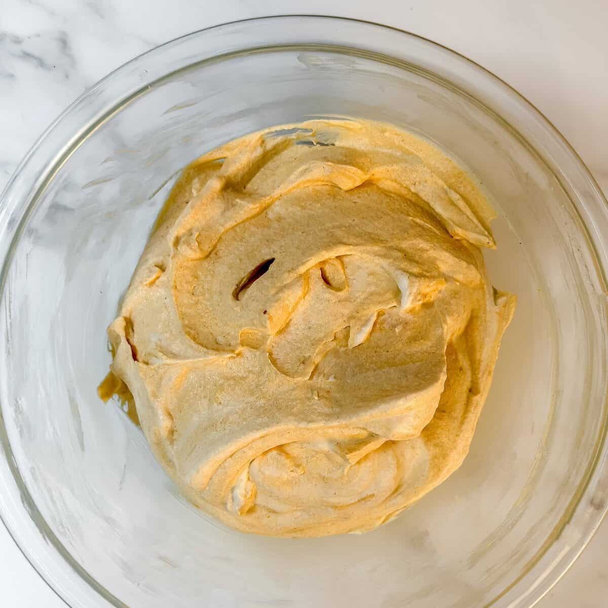 Pumpkin Chantilly Cream filling folded together and waiting for layering in a glass bowl.
