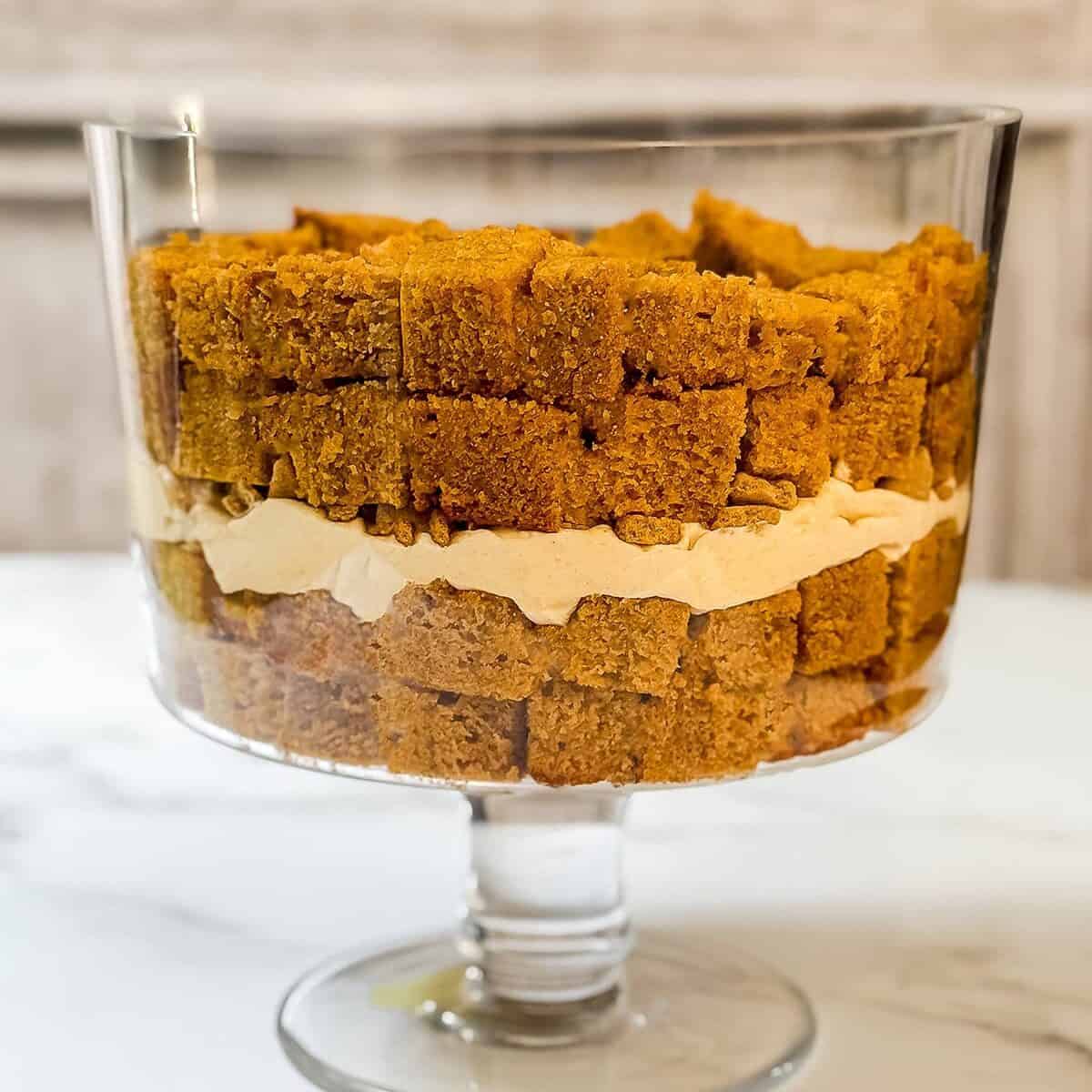 Third layer is a layer of cubed pumpkin bread in a glass trifle dish.
