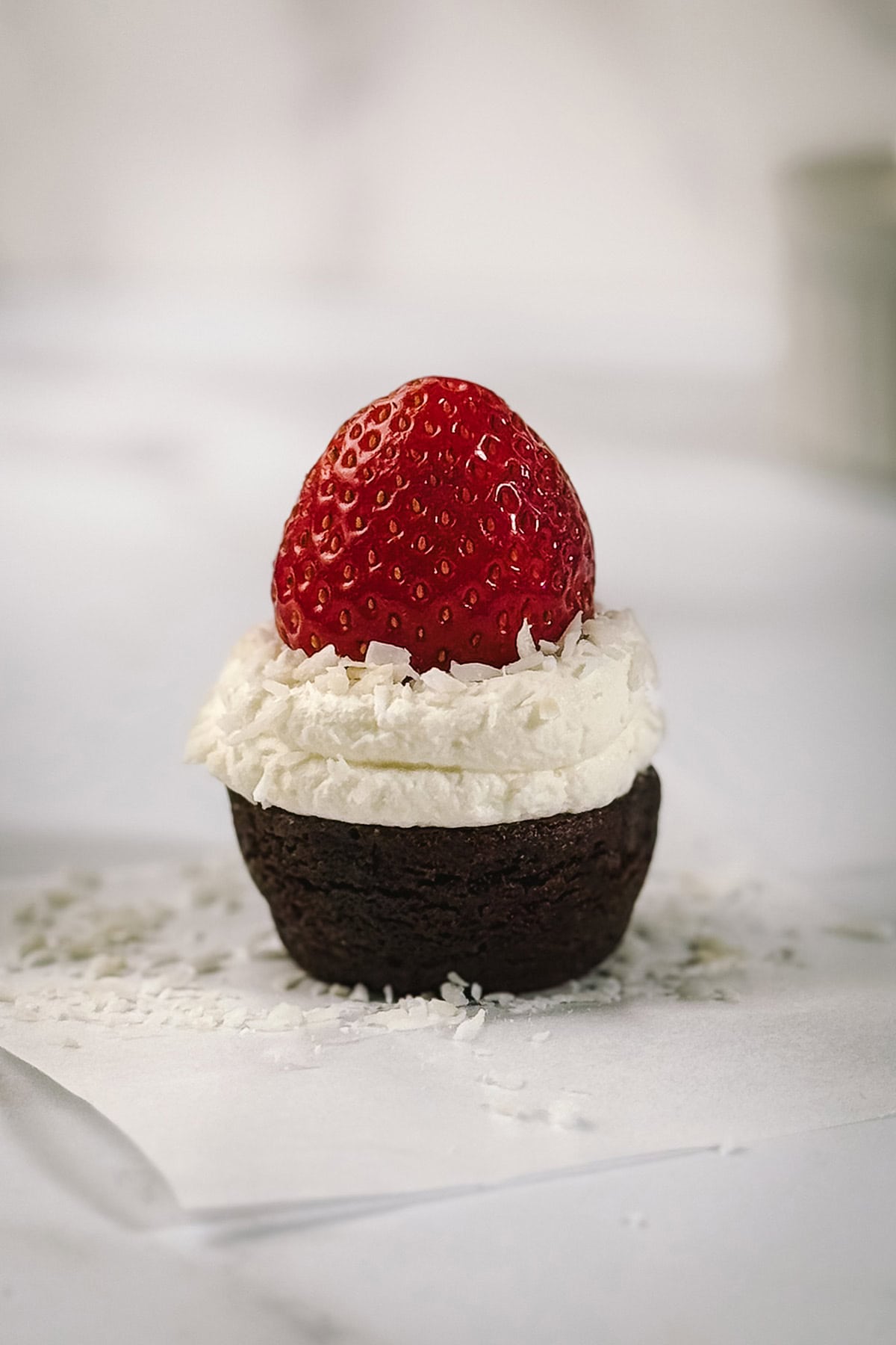 Fresh strawberry placed on top of whipped cream to form the Santa hat on a brownie bite.