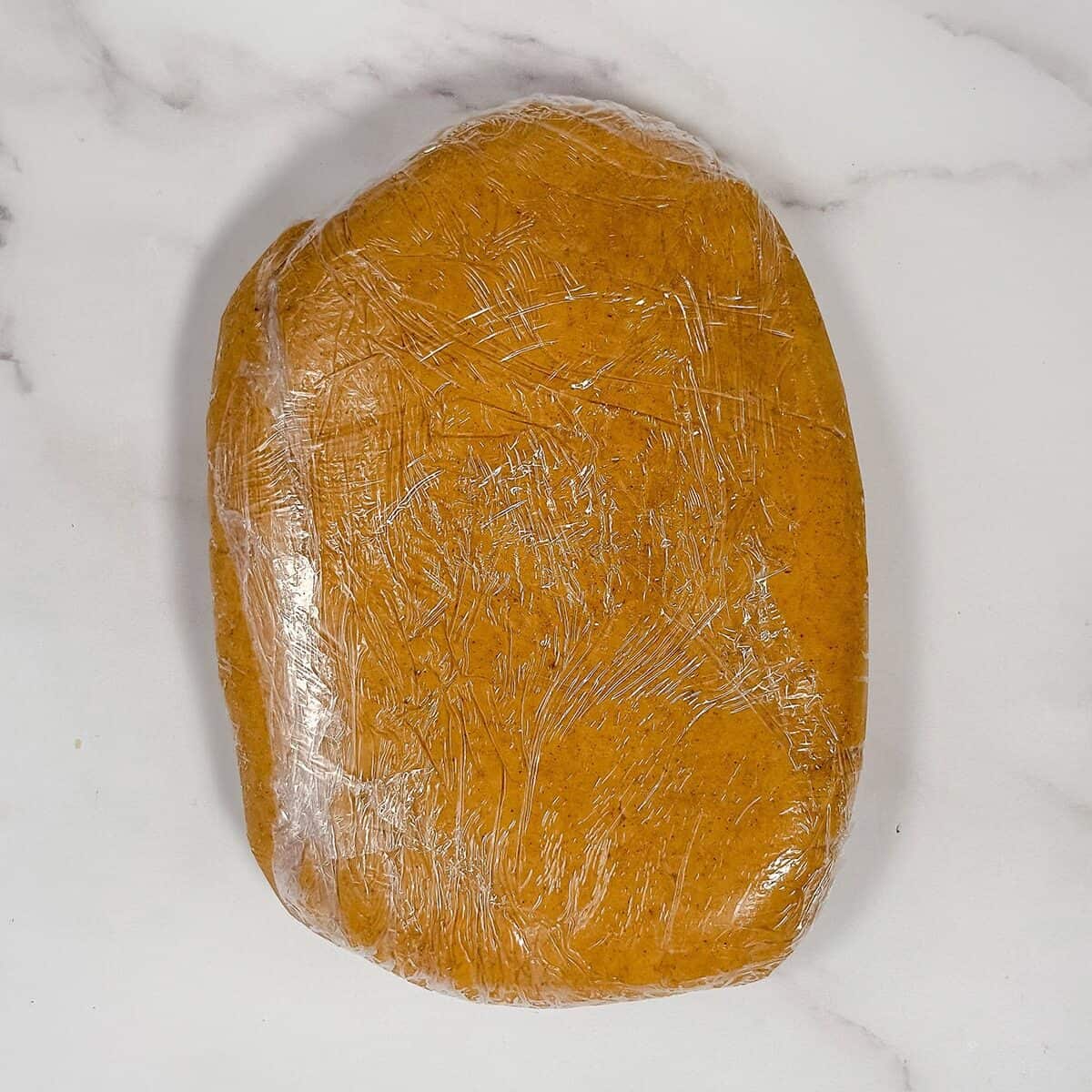 Chilled speculoos dough in plastic wrap ready for rolling.