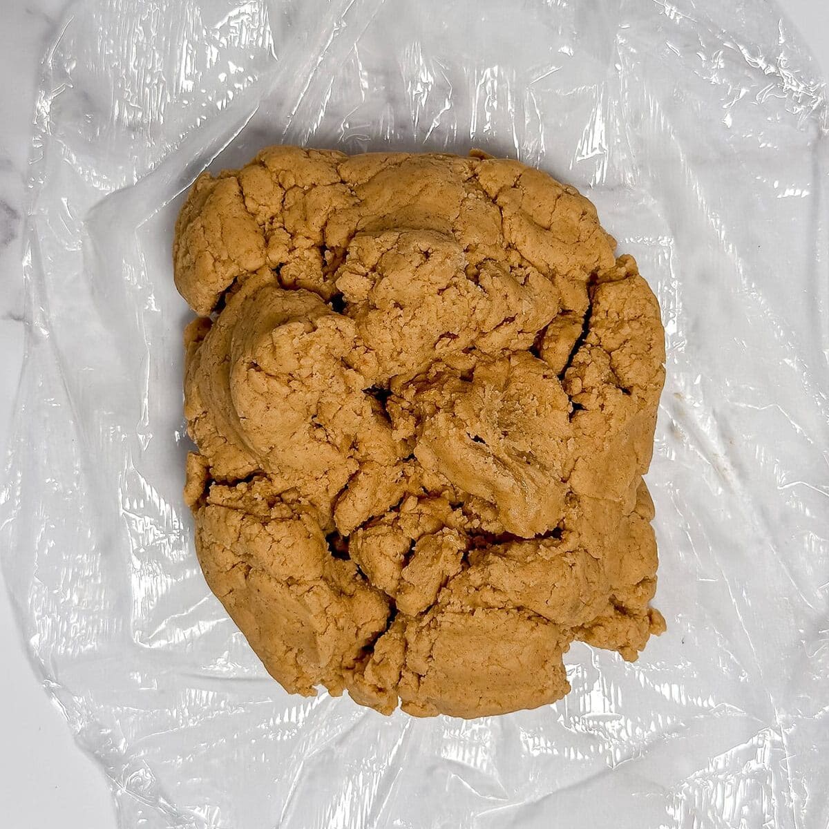 Unbaked speculoos dough in plastic wrap ready for chilling.