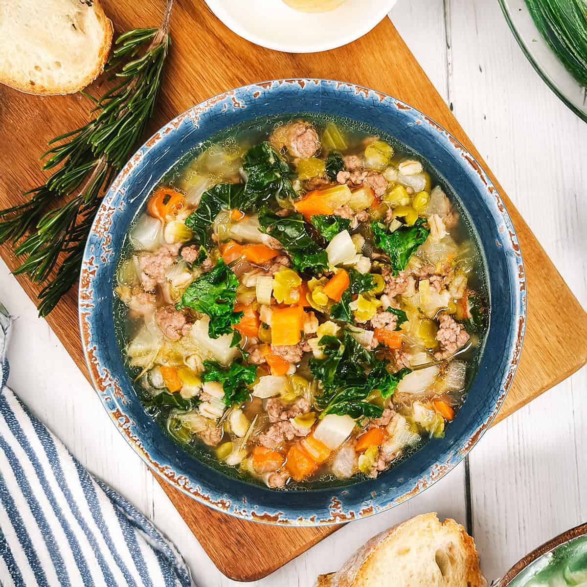 Serving Scotch Broth in a soup bowl with fresh rosemary and slices of sourdough bannock on the side.