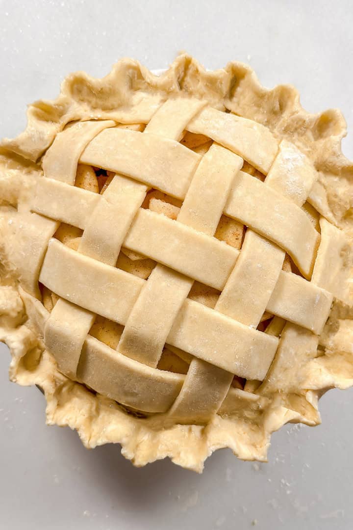 Square image of unbaked lattice topped pie with fluted edges.