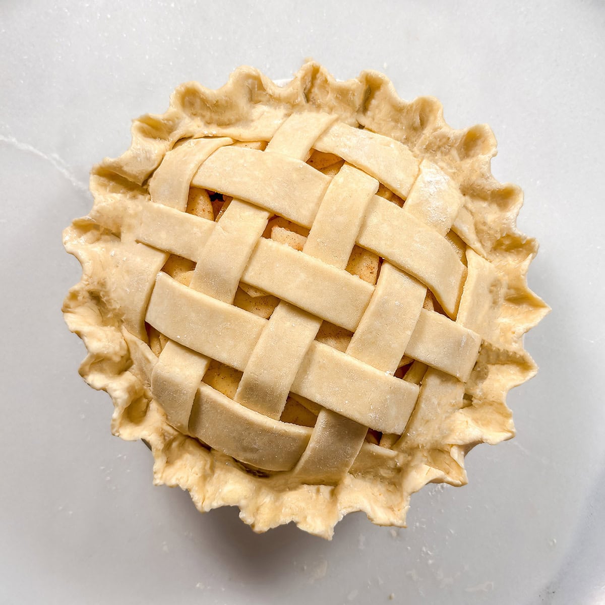 Square image of unbaked lattice topped pie with fluted edges.