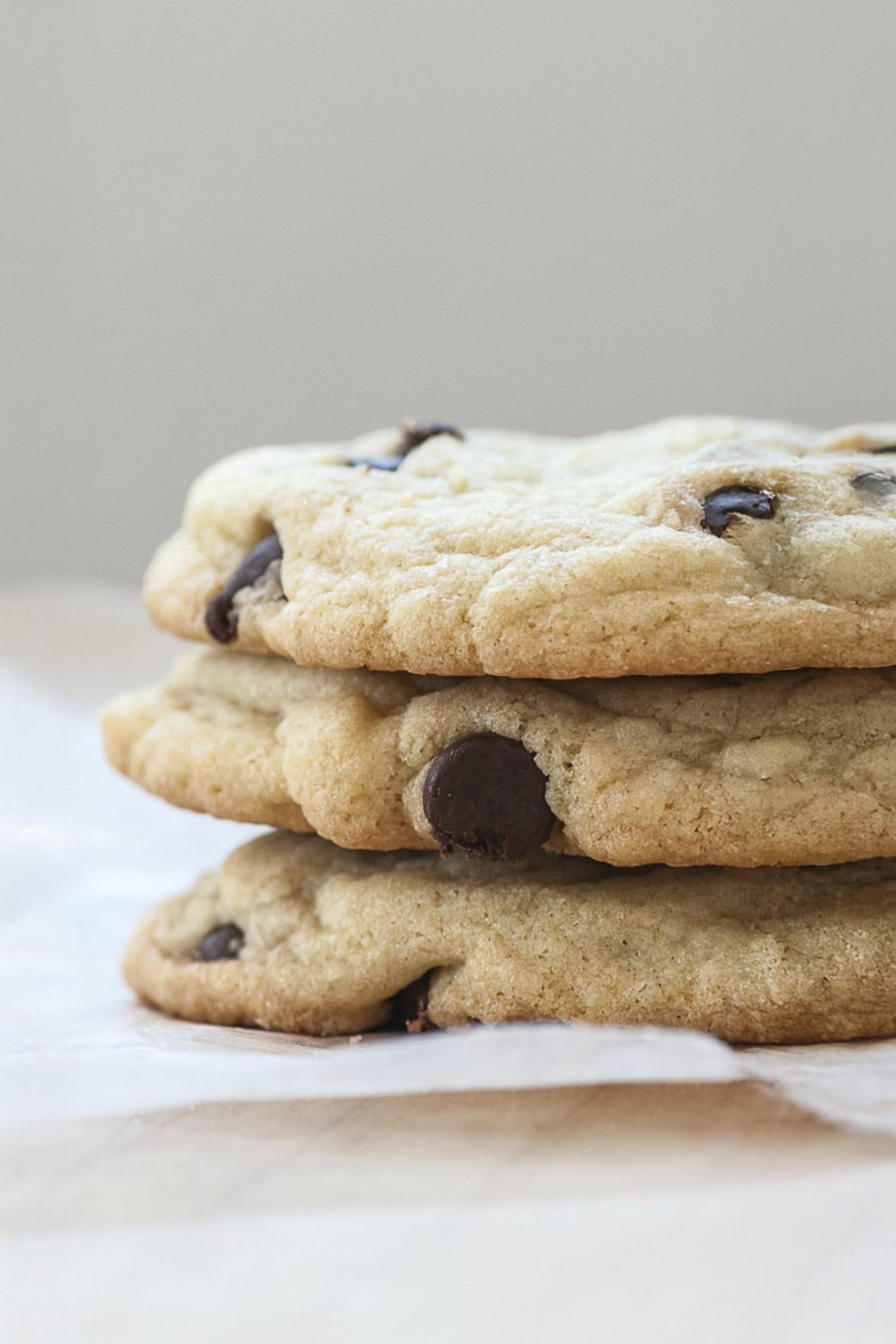 Stacked Chocolate Chip cookies on a parchment square.