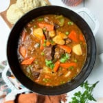 Beef stew garnished with fresh parsley in a large soup pot ready for serving.