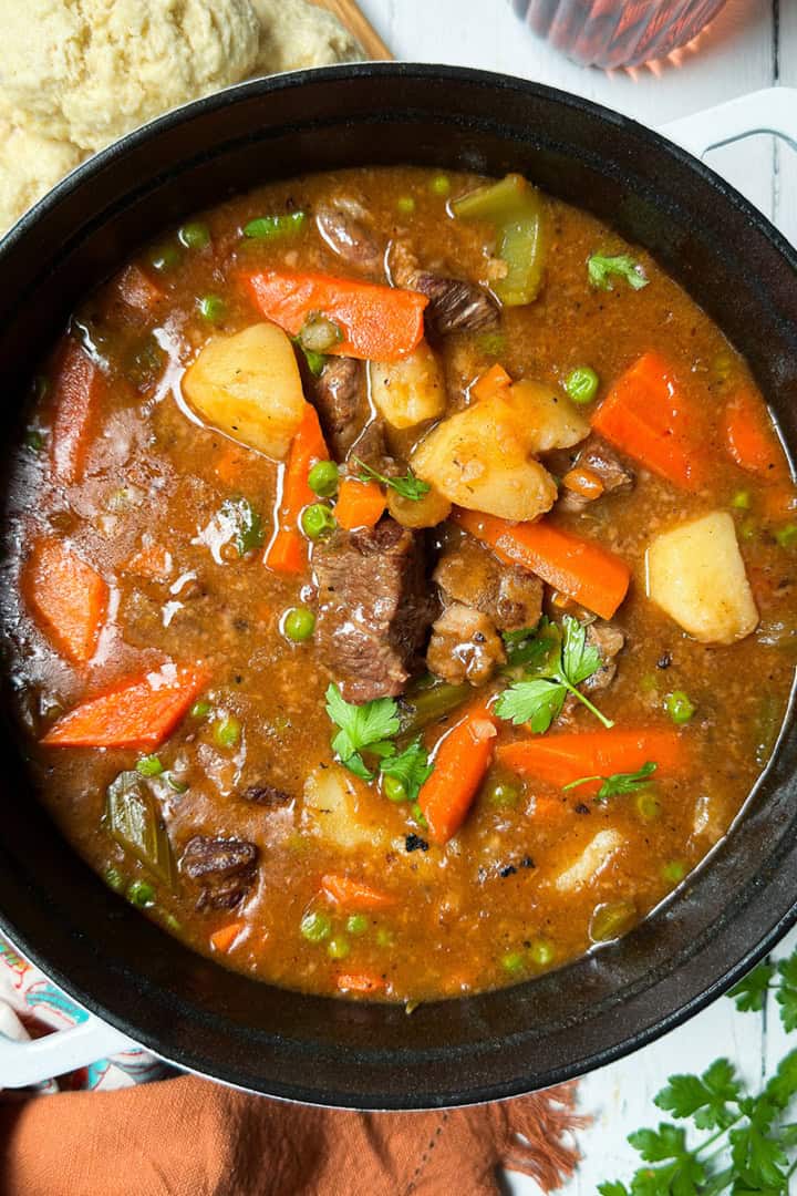 Beef stew garnished with fresh parsley in a large soup pot ready for serving.