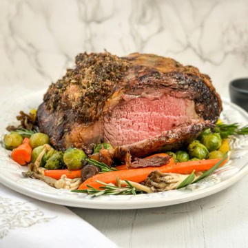 Square image of sliced prime rib roast resting on a serving platter for the holidays.