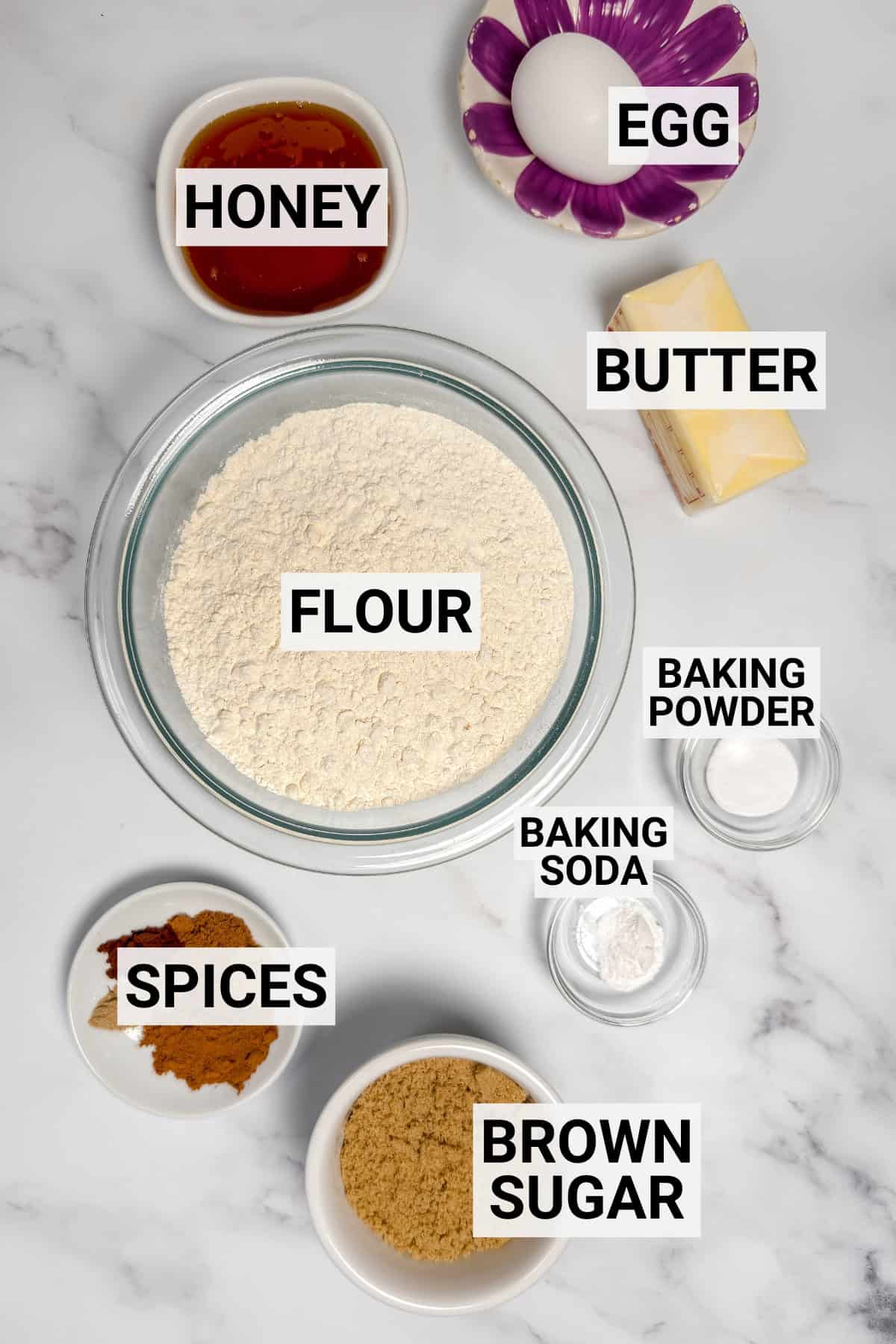Ingredients for homemade speculoos including flour, butter, honey, egg, brown sugar, baking powder and soda, and spices.