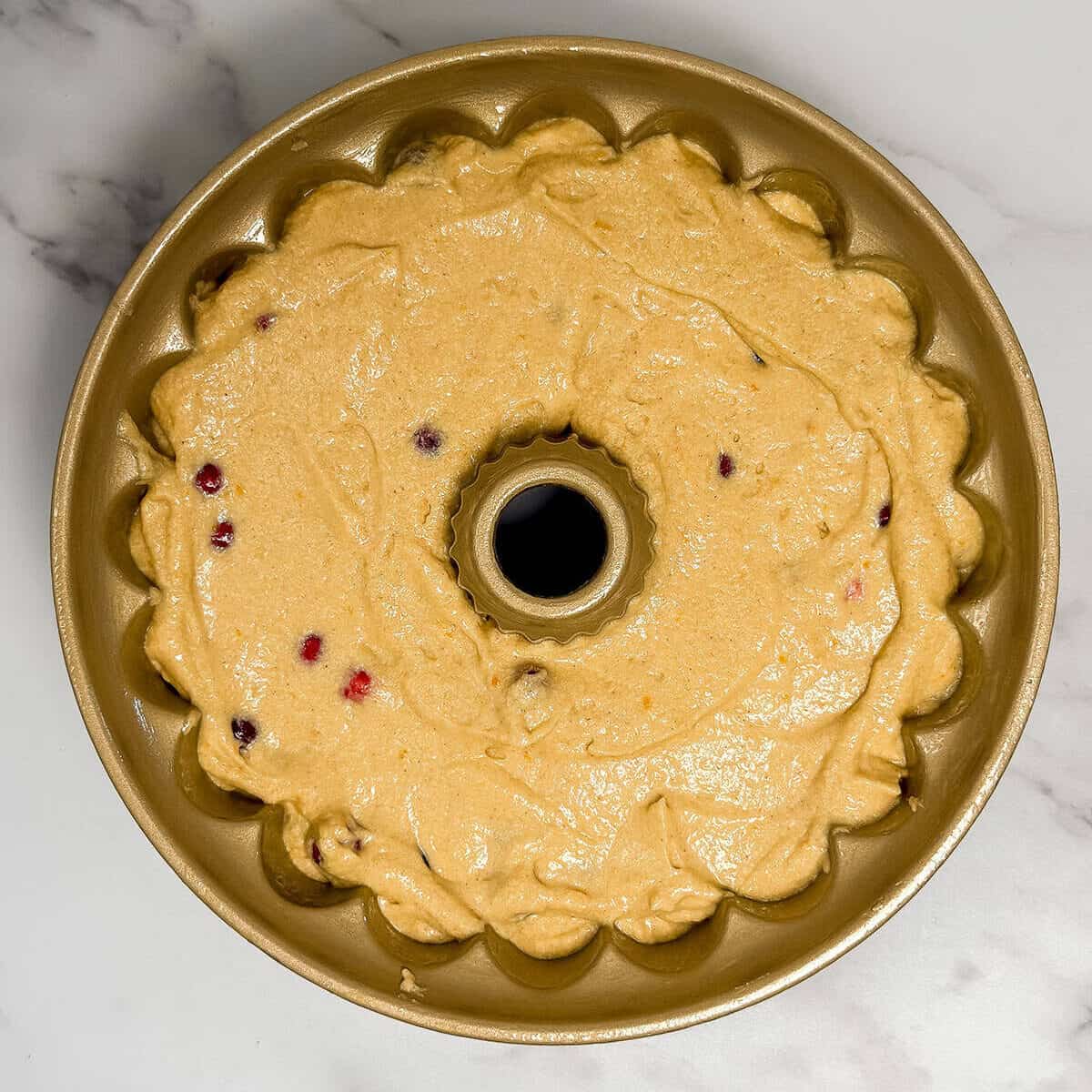 Cranberry Orange Bundt Cake batter in a 10-inch Bundt pan mold ready for the oven.