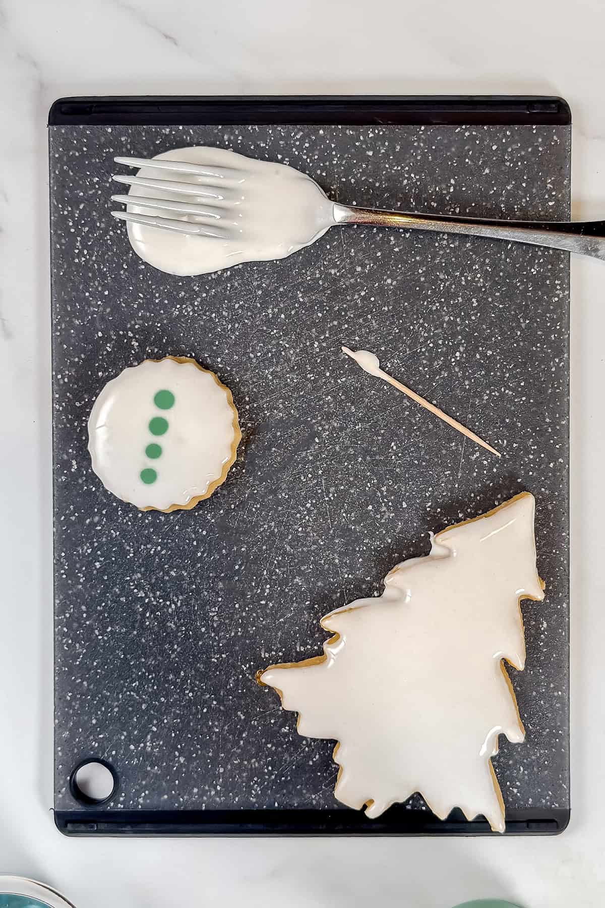 Adding green dots to white icing on the sugar cookie to swirl with a toothpick.