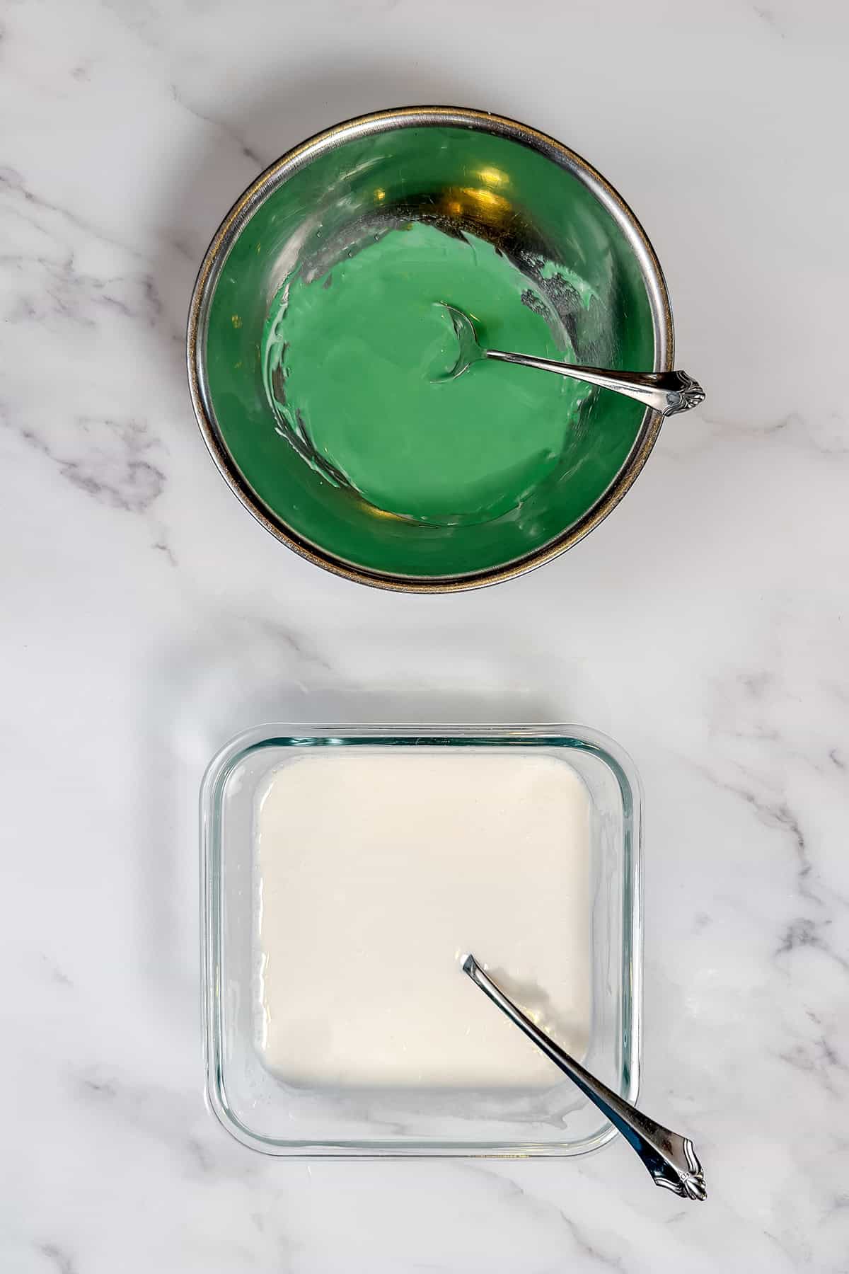 Flooding royal icing in two containers, one white, one tinted in green and ready for dipping.