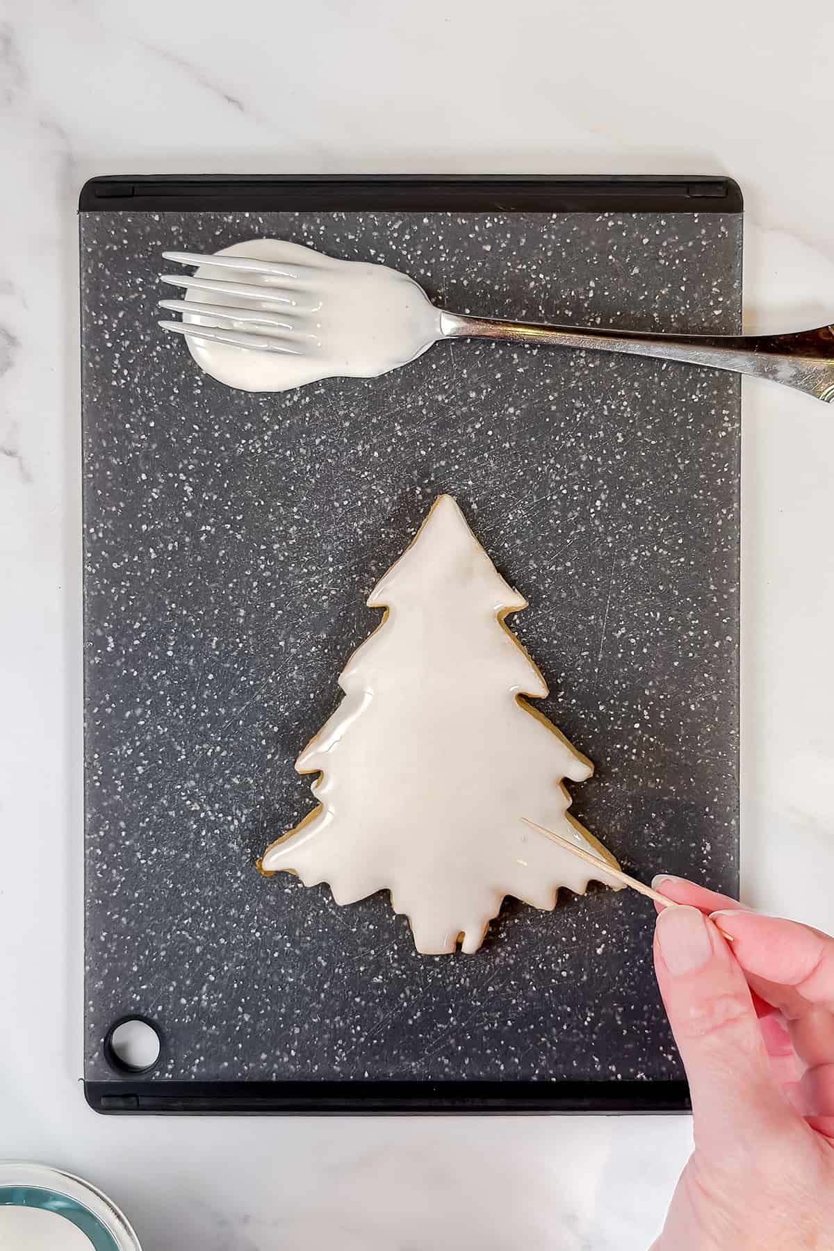 Using a toothpick on just dipped royal icing cookie to remove any air bubbles.