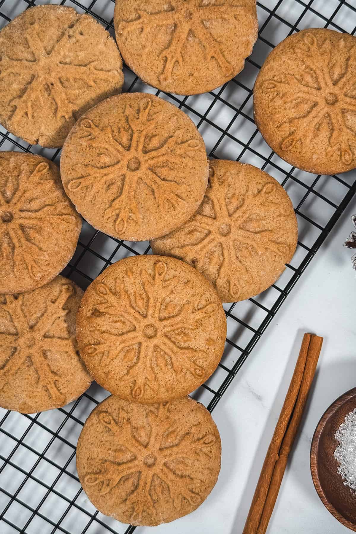 Overhead view of stamped speculoos cookies cooling on a rack, showing the snowflake pattern and golden-brown edges.