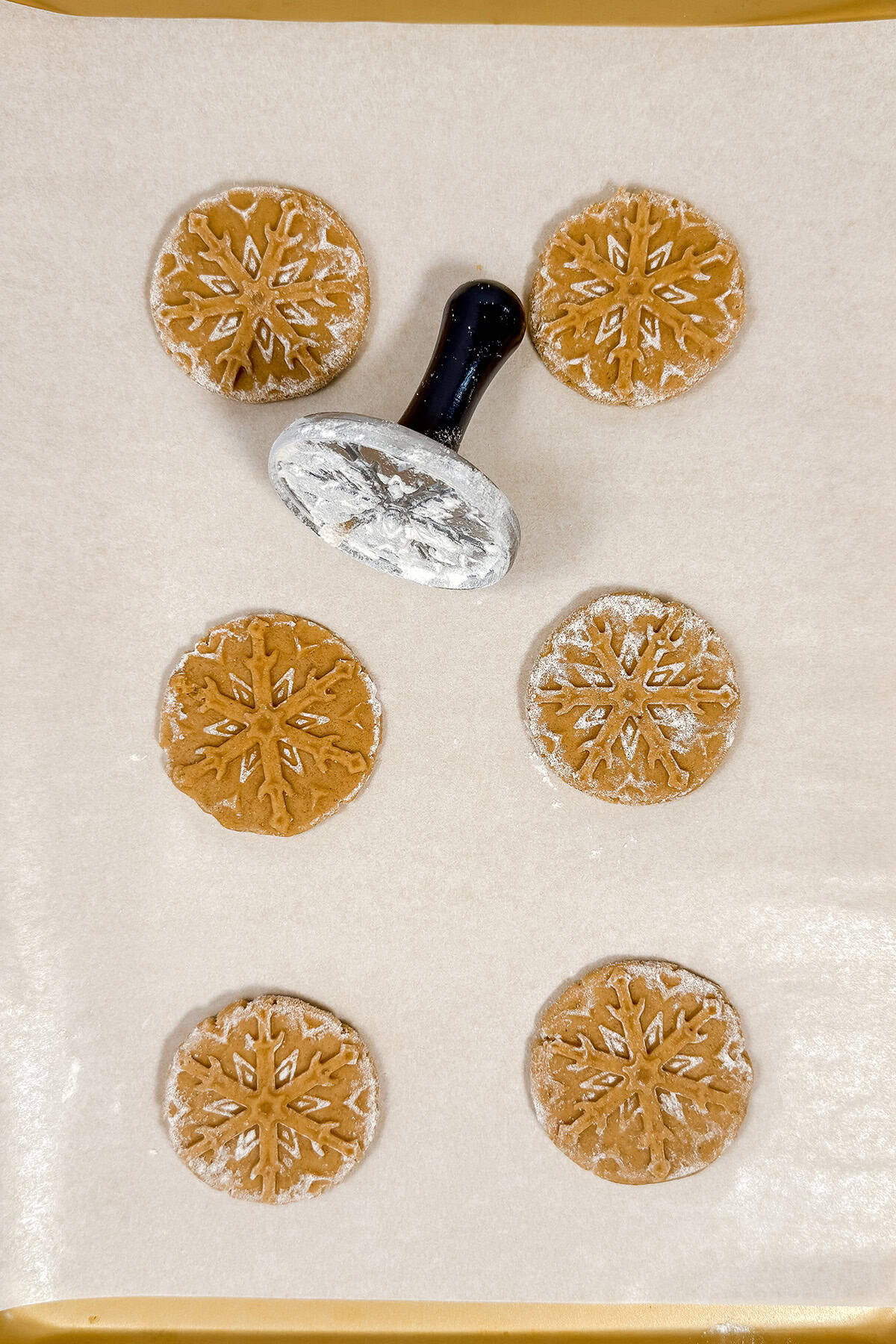 Stamping or cutting speculoos dough on a parchment lined surface.