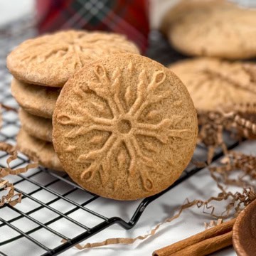 Close-up of a stamped snowflake speculoos cookie with crisp, caramelized edges, styled for holiday baking.