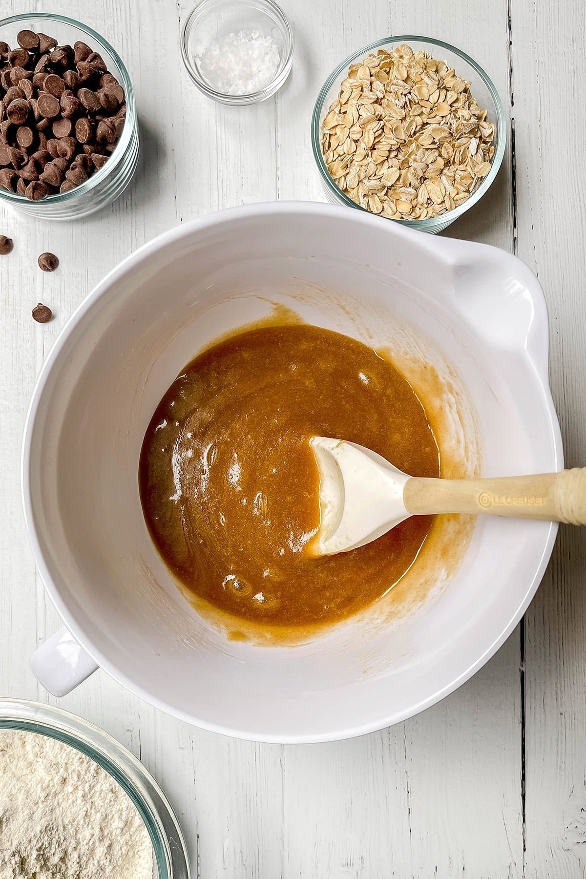 Oatmeal chocolate chip cookie bar dough with melted butter and sugar mixed in a bowl.