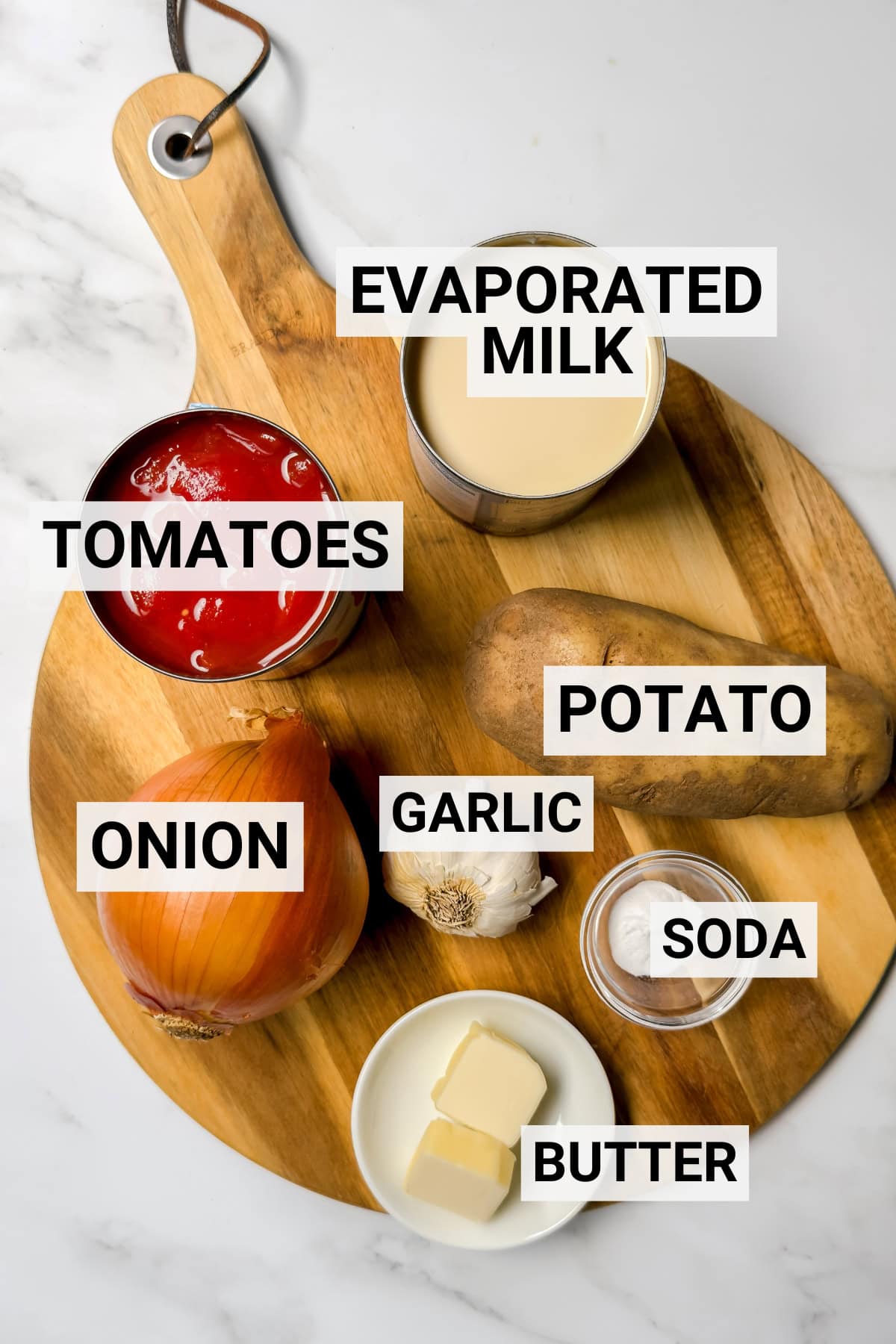 Ingredients for tomato potato soup including tomatoes, potatoes, onion, garlic, butter, evaporated milk, and baking soda.