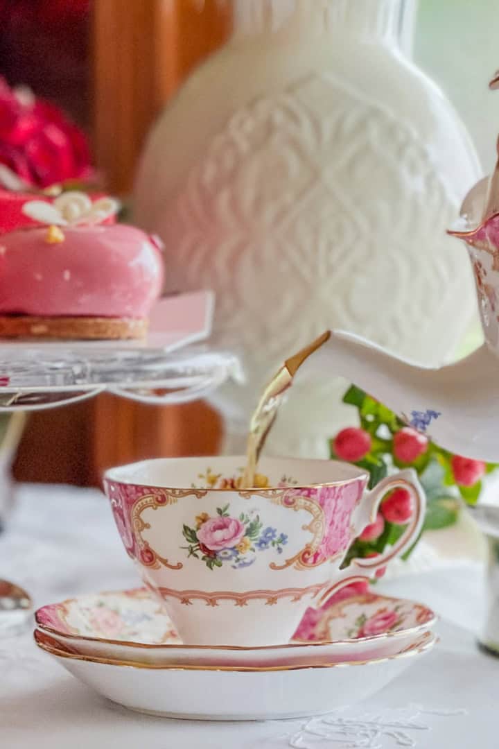 Close-up of tea being poured into a vintage floral teacup for a Valentine’s afternoon tea table.