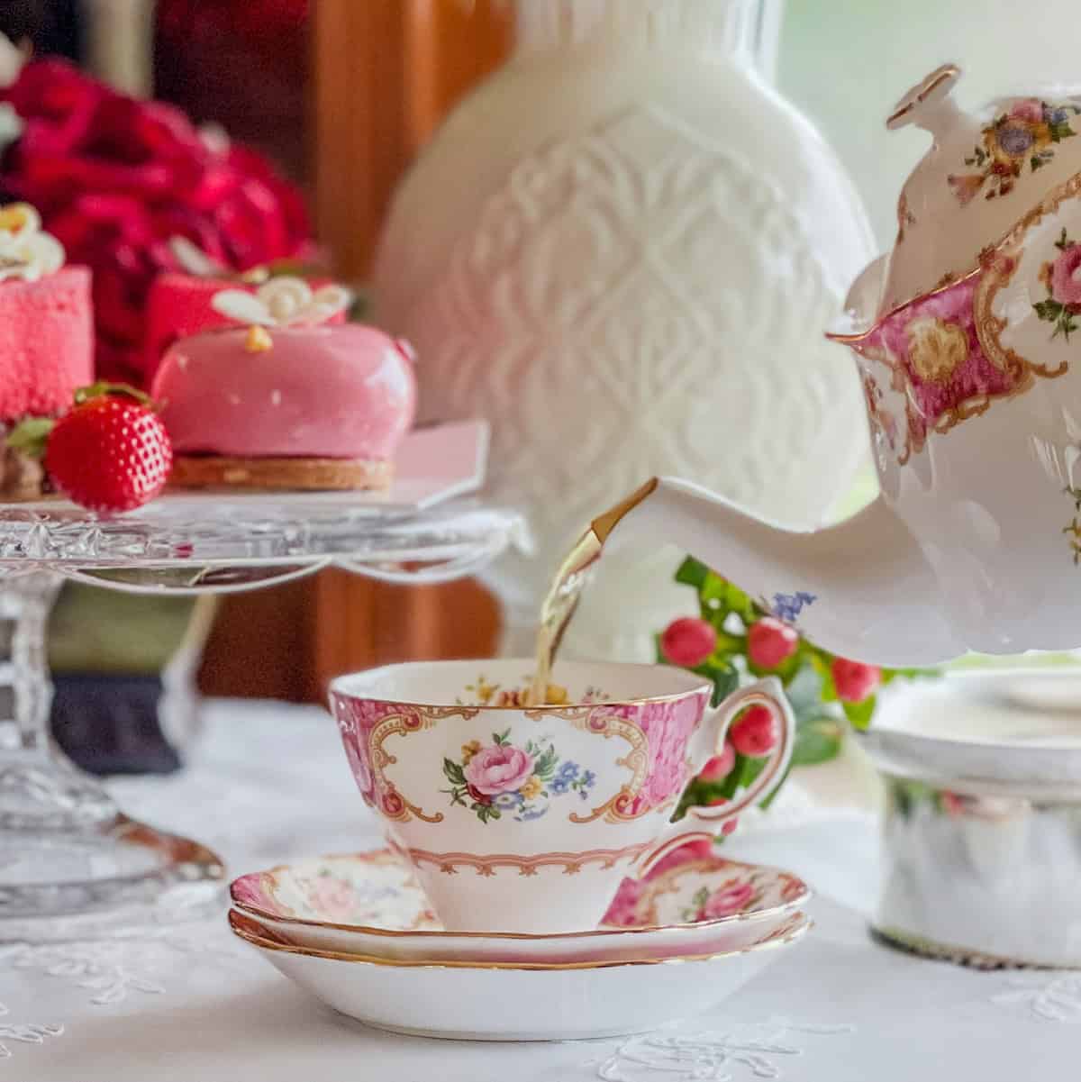 Close-up of tea being poured into a vintage floral teacup for a Valentine’s afternoon tea table.