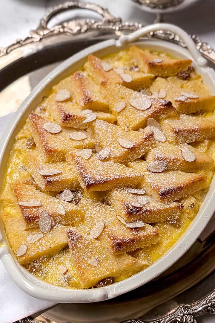 Bread and butter pudding with golden bread layers and creamy custard, dusted with powdered sugar.