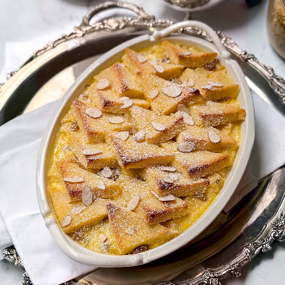 Bread and butter pudding with golden bread layers and creamy custard, dusted with powdered sugar.