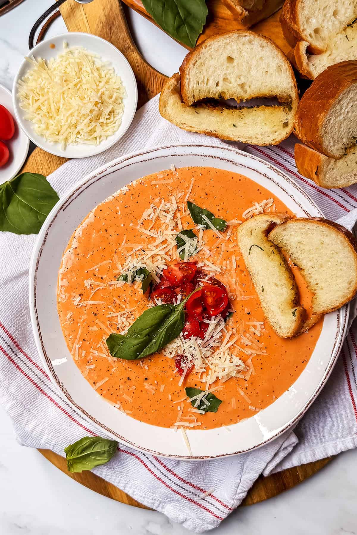 Creamy tomato soup with potatoes garnished with basil and cheese.