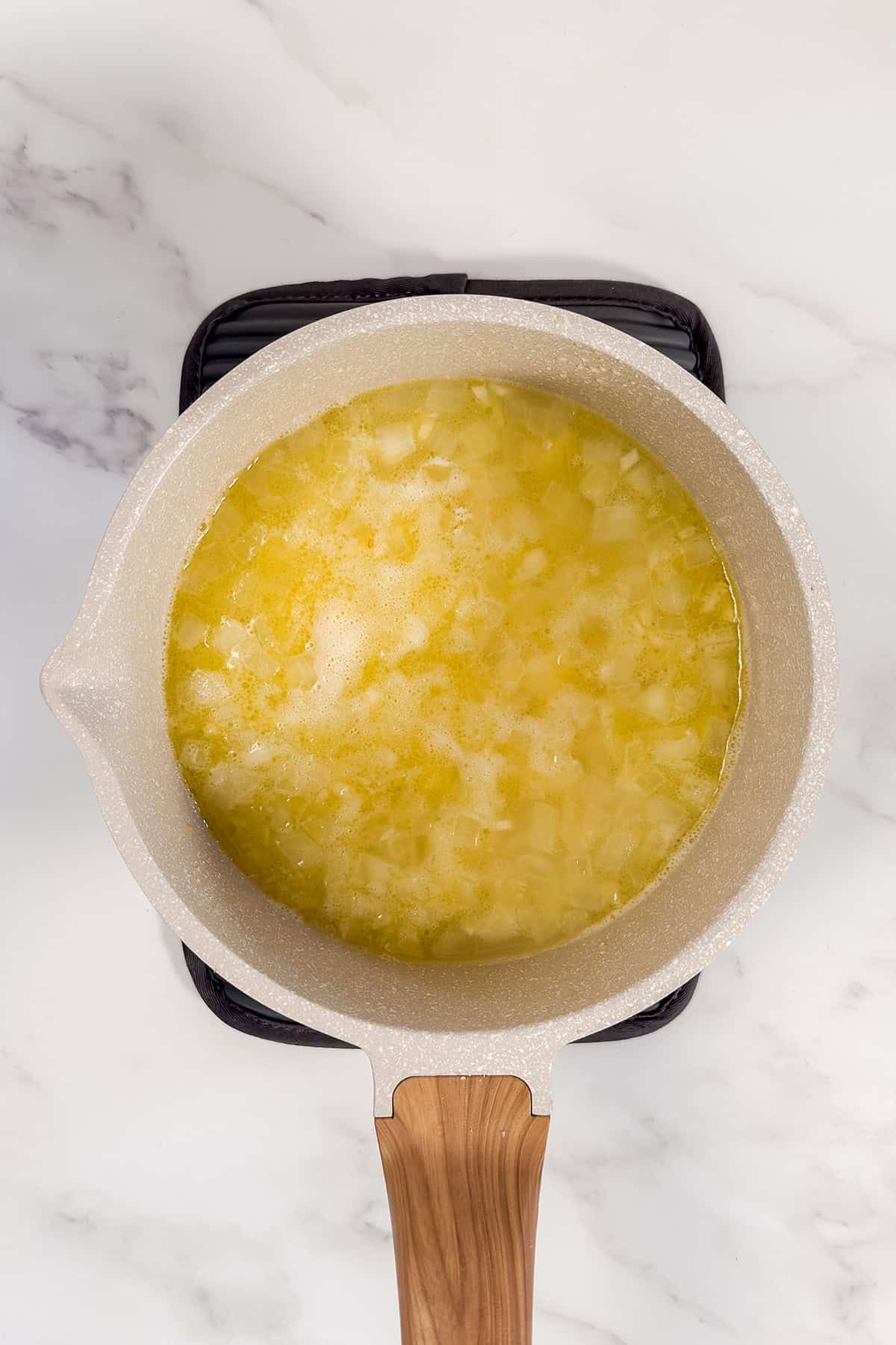 Diced potatoes simmering with onions in a soup pot.