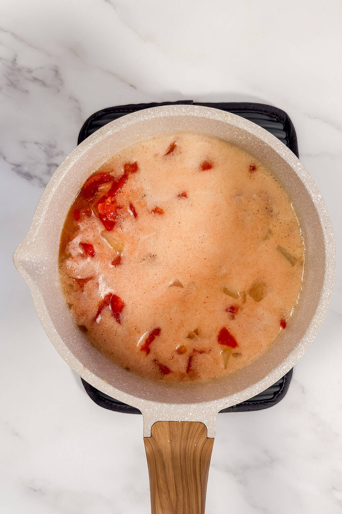 Tomatoes added to potato soup with baking soda foaming on top.