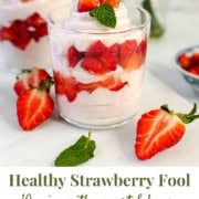 A glass filled with layers of yogurt, honey-sweetened strawberries, and mint, with more strawberries and another parfait in the background. Text reads "Healthy Strawberry Fool: 10 min. with yogurt & honey.
