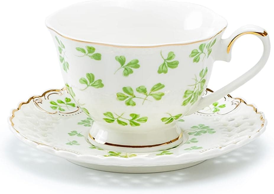 A white Irish teacup with a gold rim and handle, decorated with green shamrock patterns, sits on a matching scalloped saucer-perfect for savoring tea on a slow Sunday.