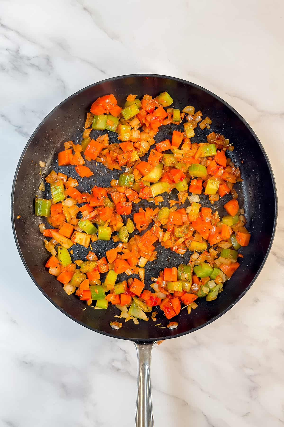 A frying pan on a marble surface contains saut&eacute;ed chopped green and red bell peppers with diced onions, making for a colorful quick skillet recipe perfect for effortless 30 minute meals.