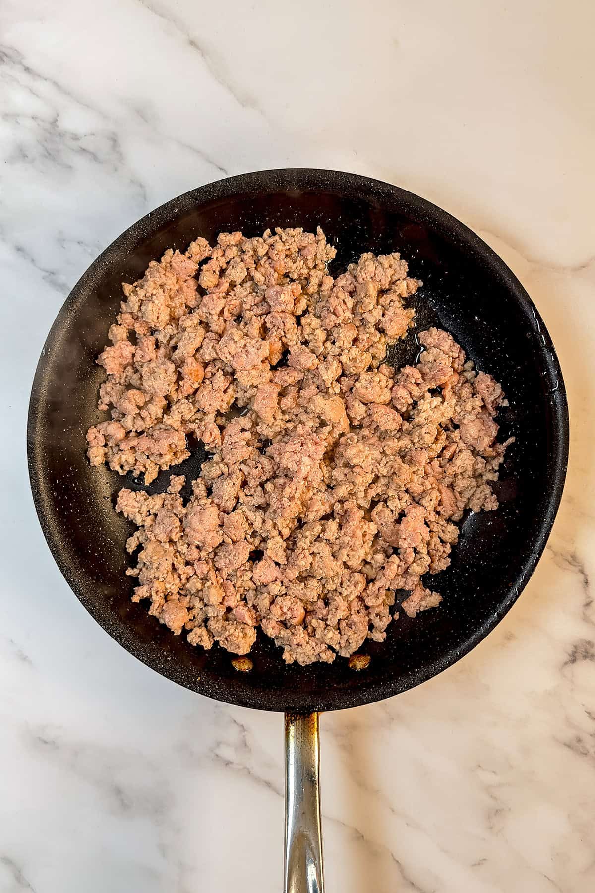 Ground meat cooking in a black skillet on a marble countertop, ready for your favorite recipe in just 30 minutes.