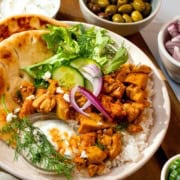 A bowl with Chicken Shawarma, rice, naan, greens, red onion, dill, and yogurt sauce, surrounded by bowls of olives and chopped red onions. Text reads "Shawarma Bowls: Quick Chicken Recipes for a 30 minute weeknight meal.