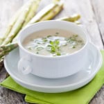 A bowl of creamy asparagus soup garnished with fresh herbs for Stephanie Wilson's Cream of Asparagus Soup.
