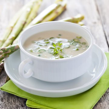 A bowl of creamy asparagus soup garnished with fresh herbs for Stephanie Wilson's Cream of Asparagus Soup.
