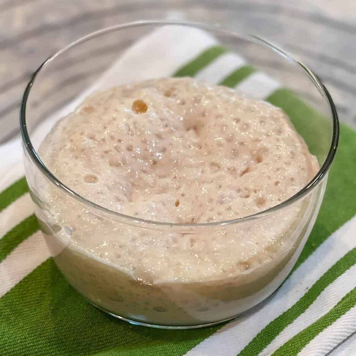 Yeast proofing in a small glass bowl with sugar to active the yeast.