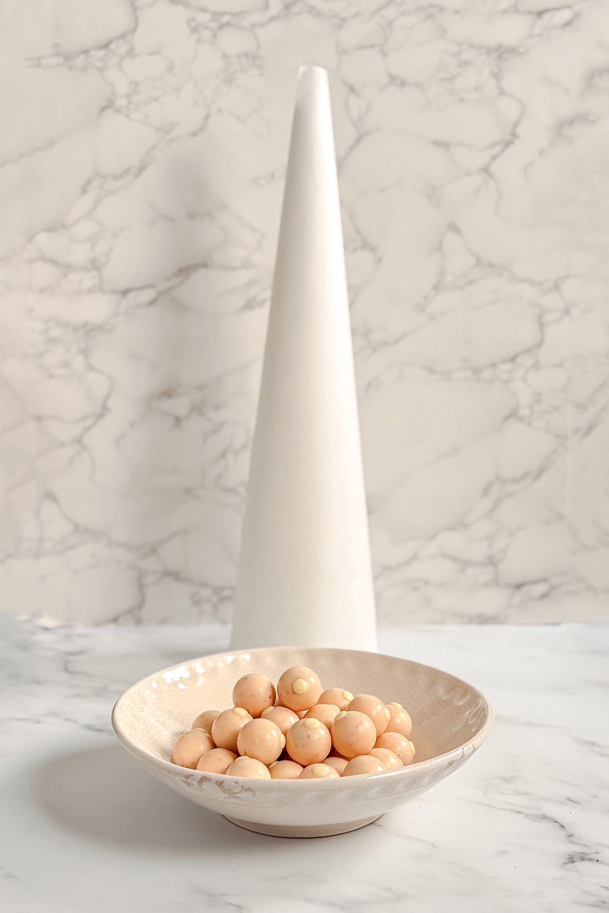 Wrapped chocolate truffles beside a parchment-covered cone for a bonbon tree.