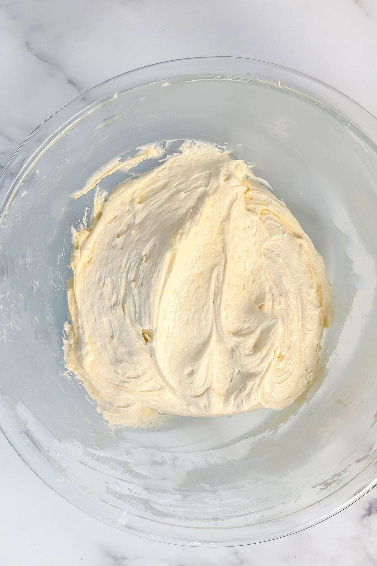 A clear glass bowl with coconut cream cheese buttercream frosting.