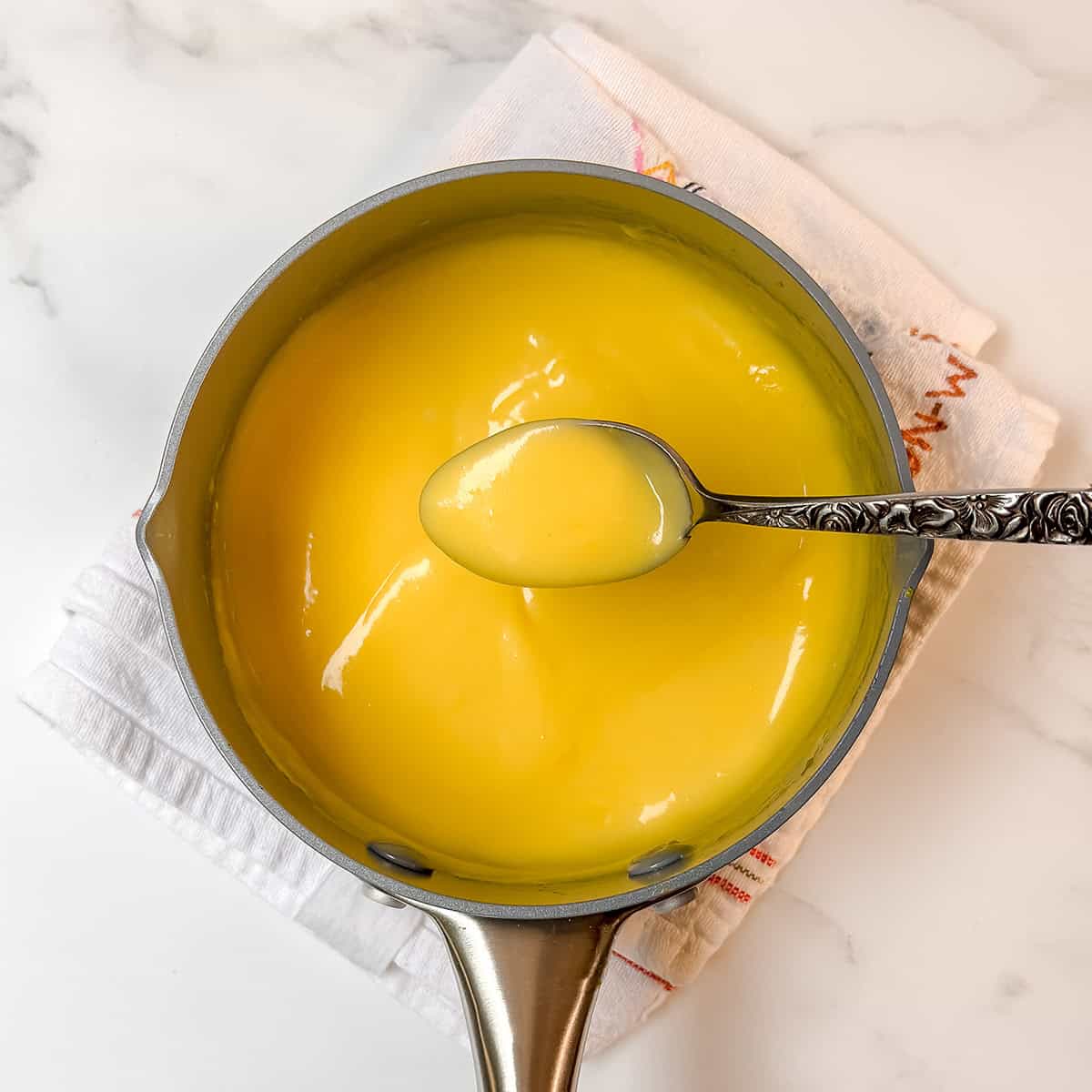 Thick and creamy hollandaise sauce cooking in a saucepan.