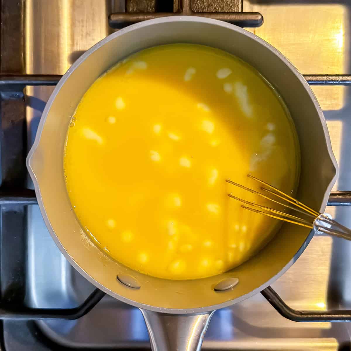 Butter melting into egg yolks while cooking stovetop hollandaise sauce.