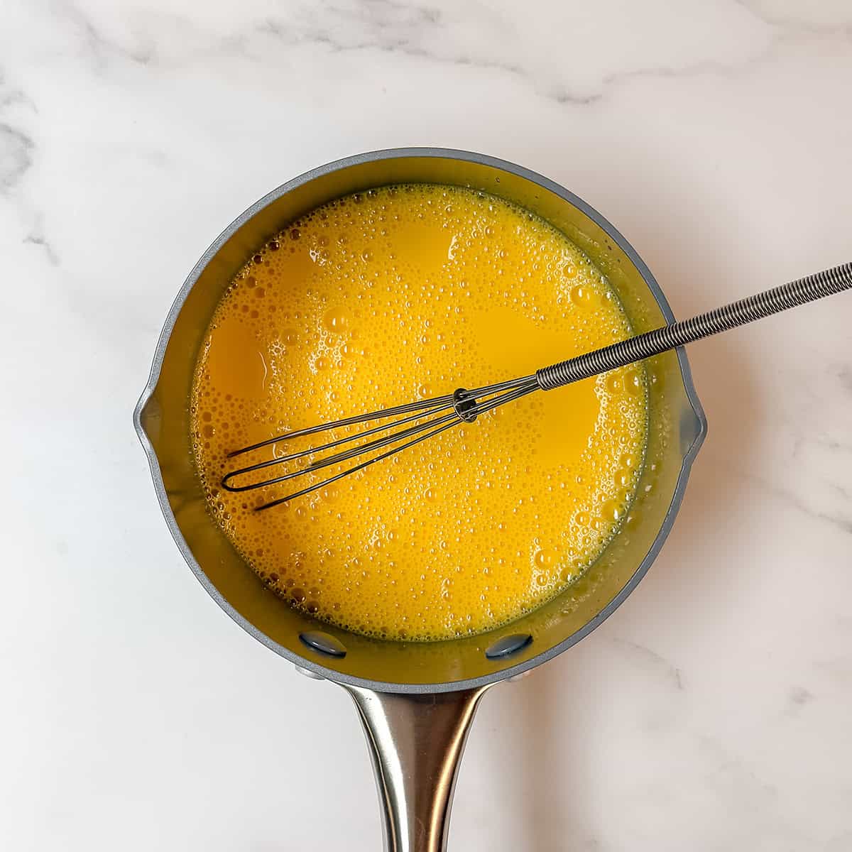Egg yolks whisked in a saucepan for stovetop hollandaise sauce.