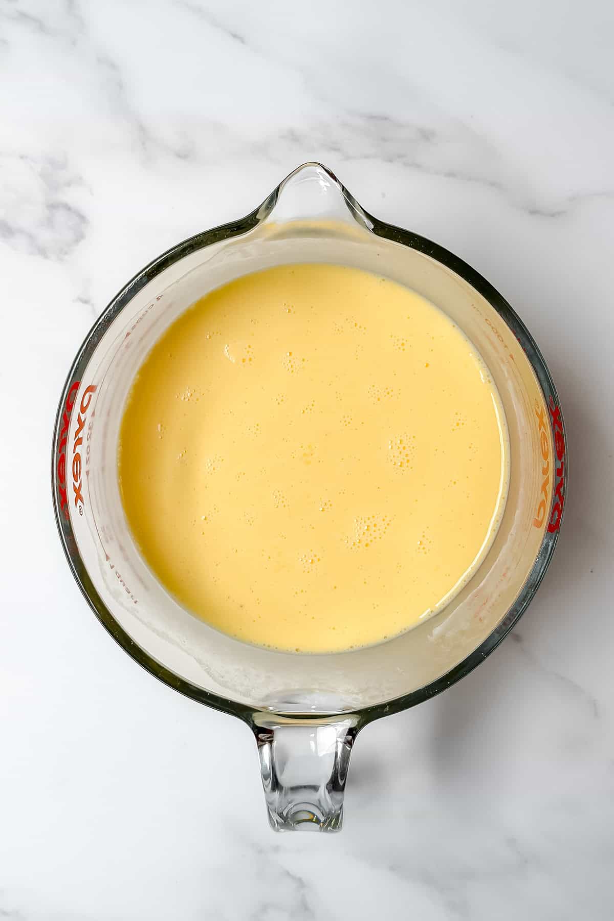 A glass Pyrex measuring cup filled with the egg mixture for this crustless quiche recipe. 
