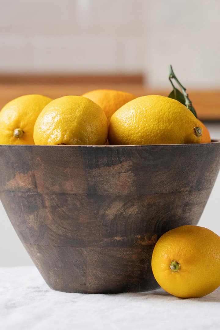 A wooden bowl filled with lemons sits on a white surface for 31Daily's Sunday Edit Spring Garden Table.