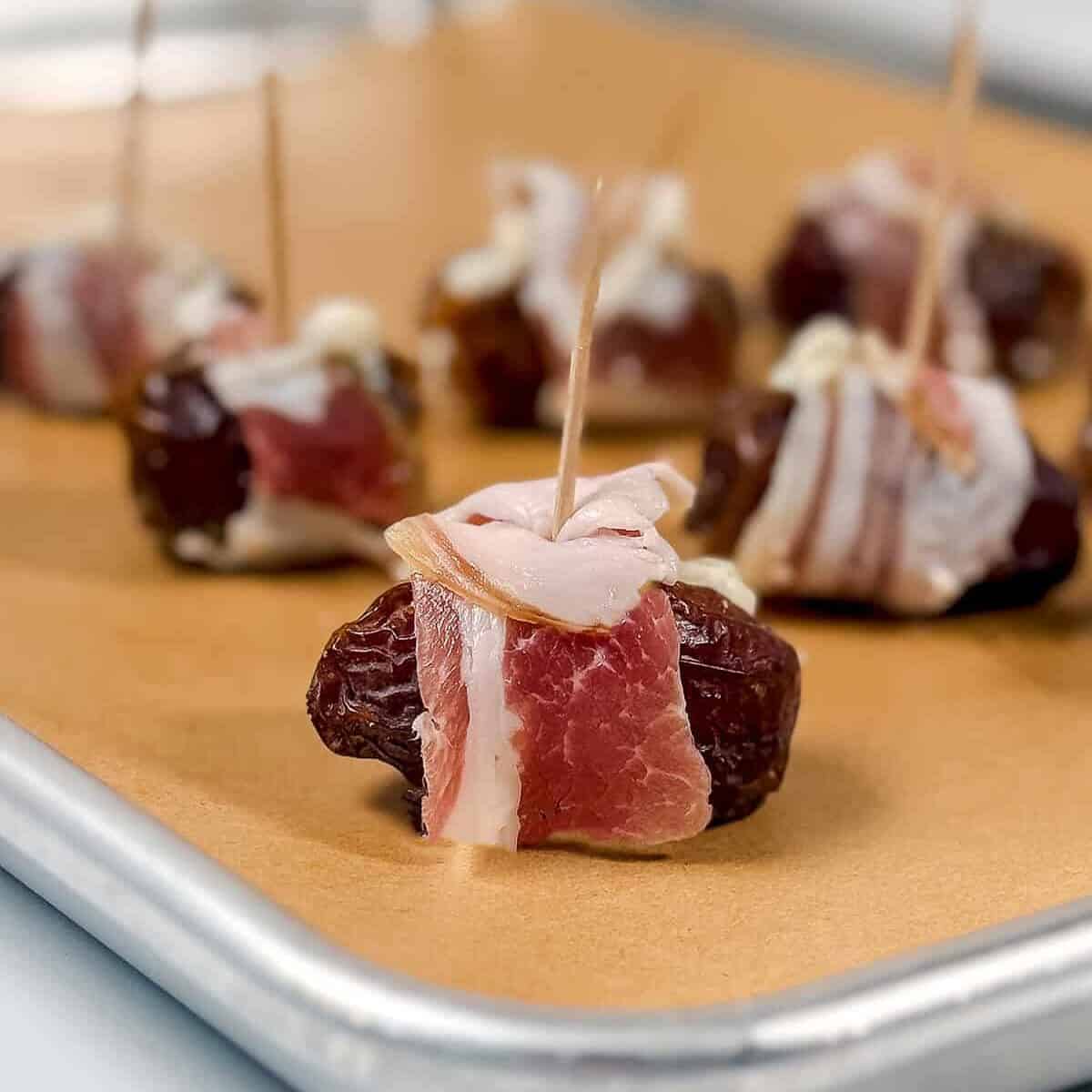 Several stuffed dates secured with skewers and arranged on a foil-lined baking sheet-an irresistible appetizer for any gathering.