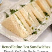 Rectangular white platter with neatly arranged Kentucky Benedictine tea sandwiches, garnished with fresh herbs and edible flowers; text overlay reads “Benedictine Tea Sandwiches.”.